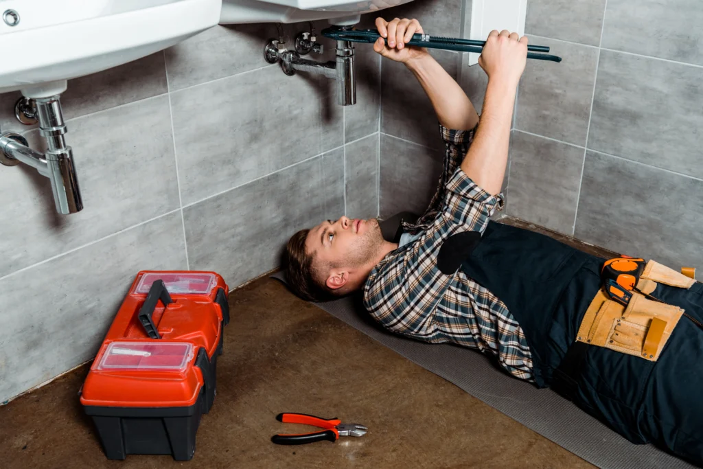 A plumber laying down and checking the leakage of the faucet.